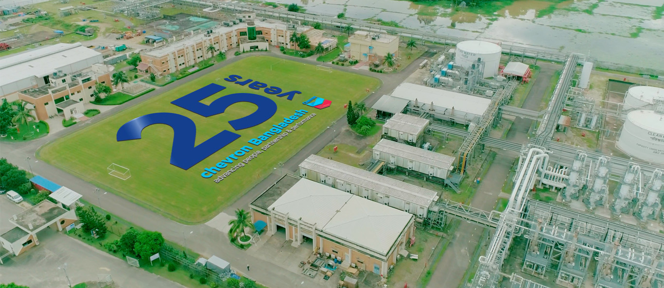 25 years Chevron Bangladesh sign in an open field next to a production facility